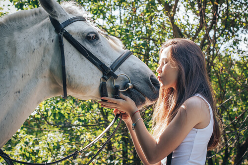 Chica dándole un beso a su caballo (terapia equina).