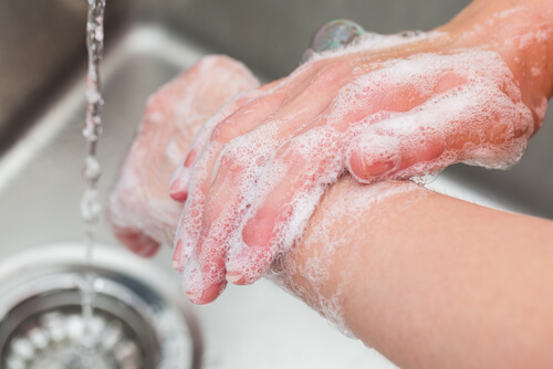 Persona lavándose las manos con agua y jabón.
