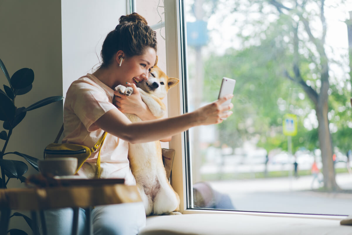 Una mujer se hace una foto con un perro en una cafetería.