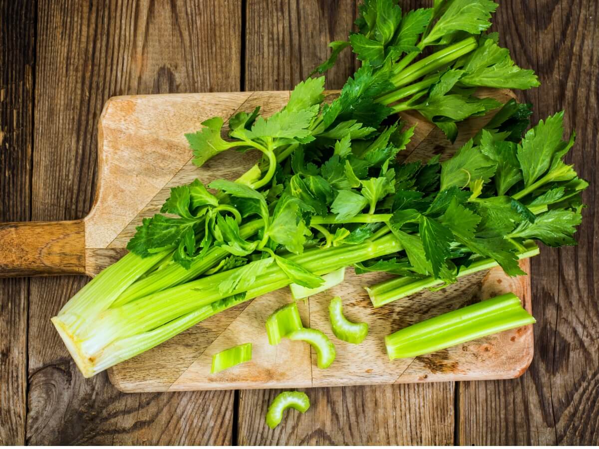 Alcuni tagliano il sedano su un tagliere.