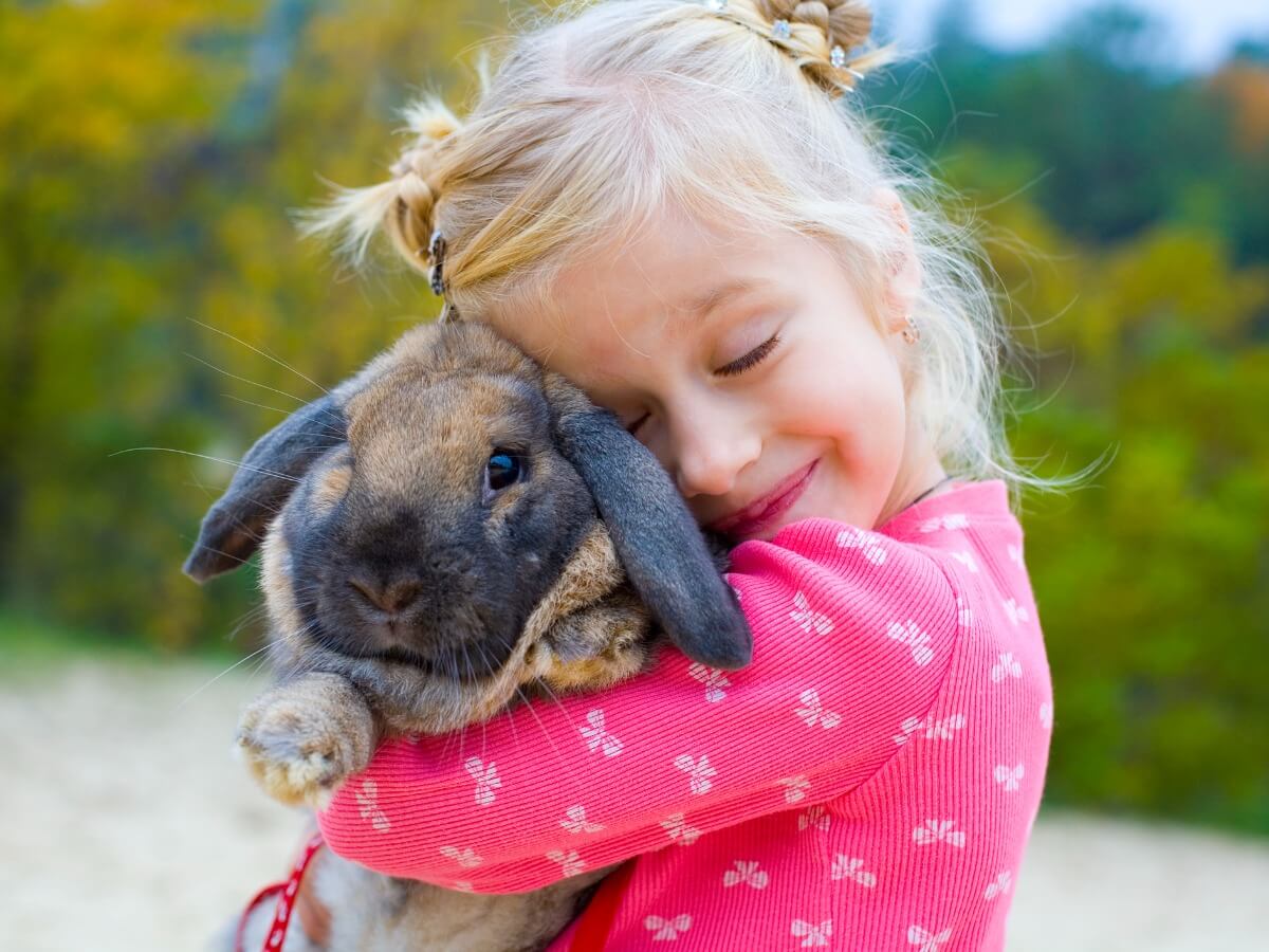 Una niña abrazando un conejo.