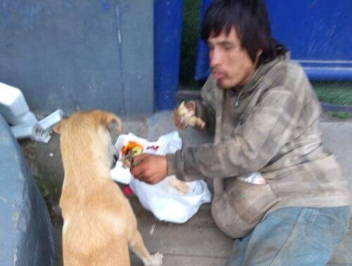 El hombre sin hogar comiendo junto a su perro.