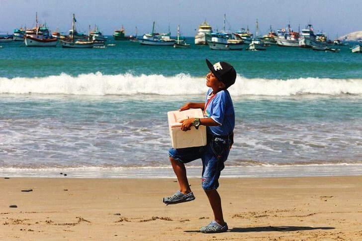 El niño vendiendo los helados en la playa.