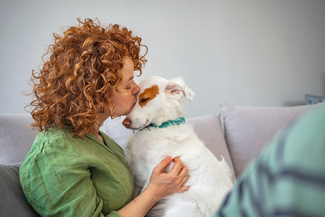 A woman kissing a dog.