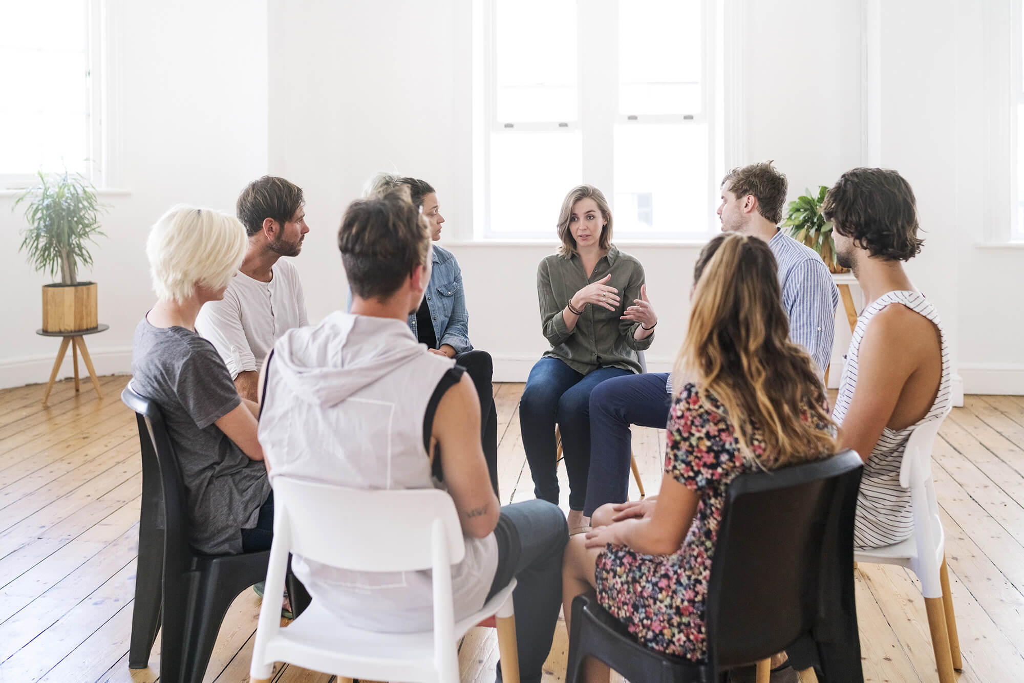 A group of adults sitting in a circle sharing during a support group.