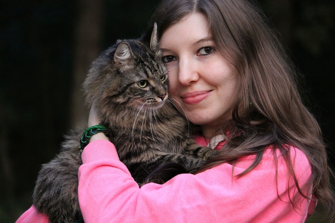 Mujer abraza a su gato. 