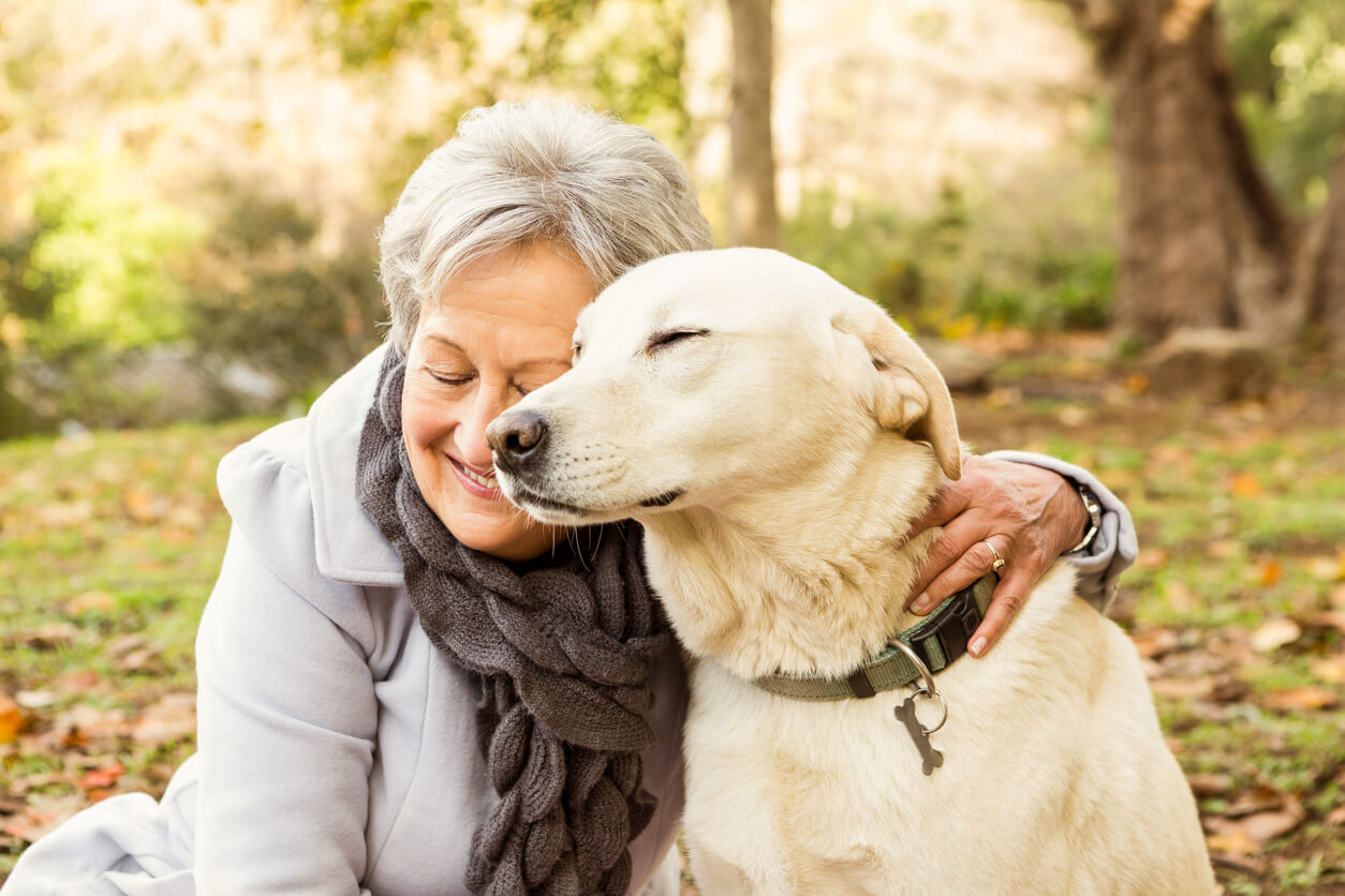 Una donna anziana abbraccia il suo cane, in segno di amore per il suo cane.